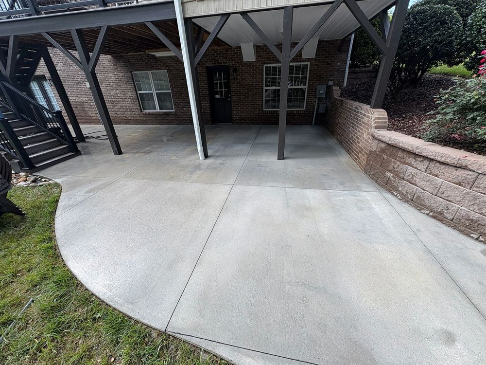 A large concrete patio under a deck, cleaned